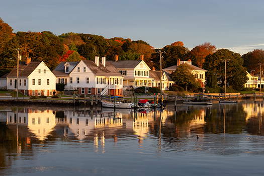 Mystic Connecticut with white houses lining the edge of the water with docs and boats.