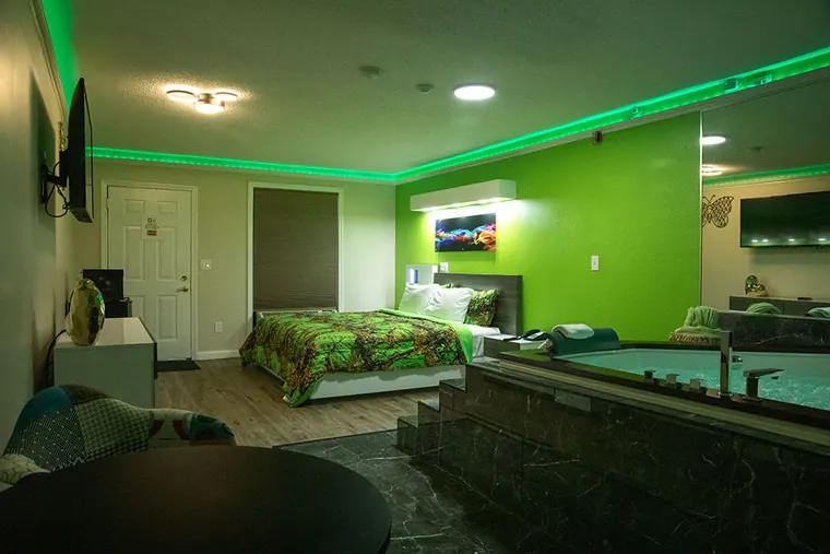 Large room with a black marble step-up Jacuzzi at one end and color-changing LED lights around the ceiling