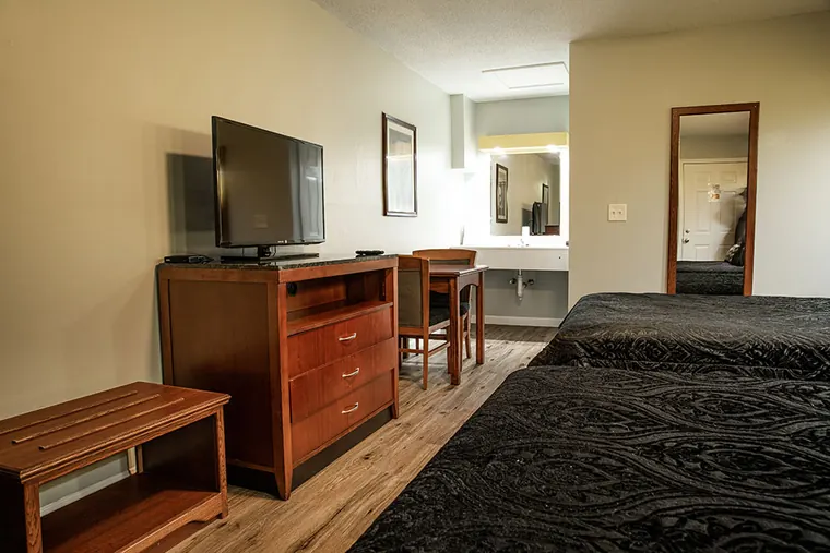 The same room showing the foot of the two beds, dresser, flat-screen TV and the bathroom area