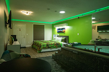 Large room with a black marble step up jacuzzi on one end. LED lights around the upper parimeter of the room change to different colors.