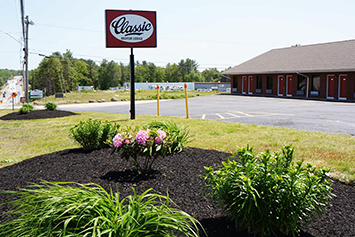 Outside of motel with the sign and well landscaped area with flowers and shrubs