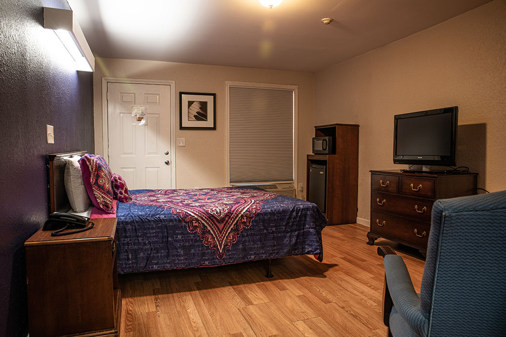 Single bed, tv on dresser, microwave and mini-fridge