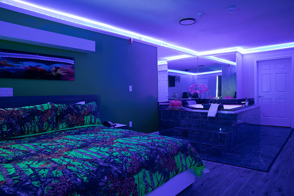The jacuzzi room has different colored lighting from red, blue and green. The lights are along the ceiling. This image shows the blue lighting